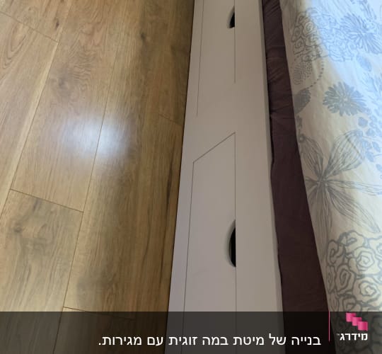 מגירות עץ מובנות מתחת למיטה על רצפת עץ